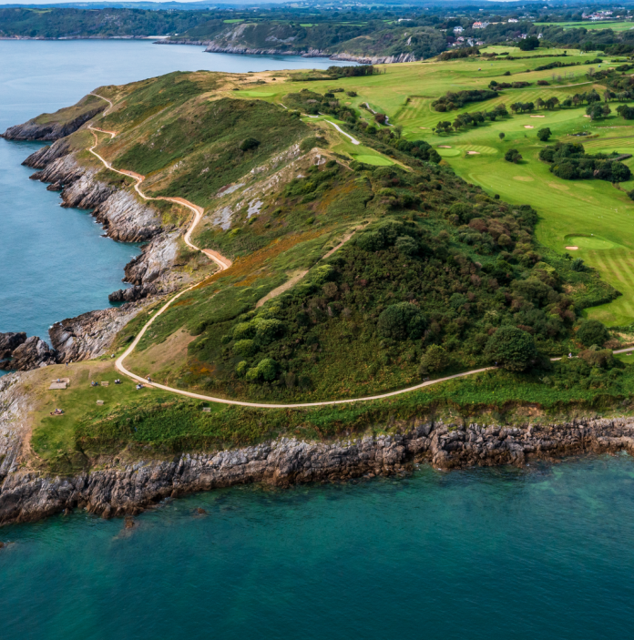Aerial shot of a headland, coast path and golf course.