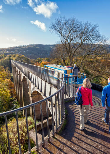 View of two people walking on the Pontcysyllte aqueduct in autumn.