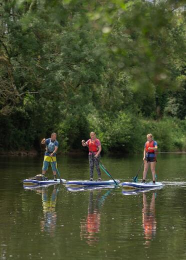 Group of people stand-up paddleboarding on a river.