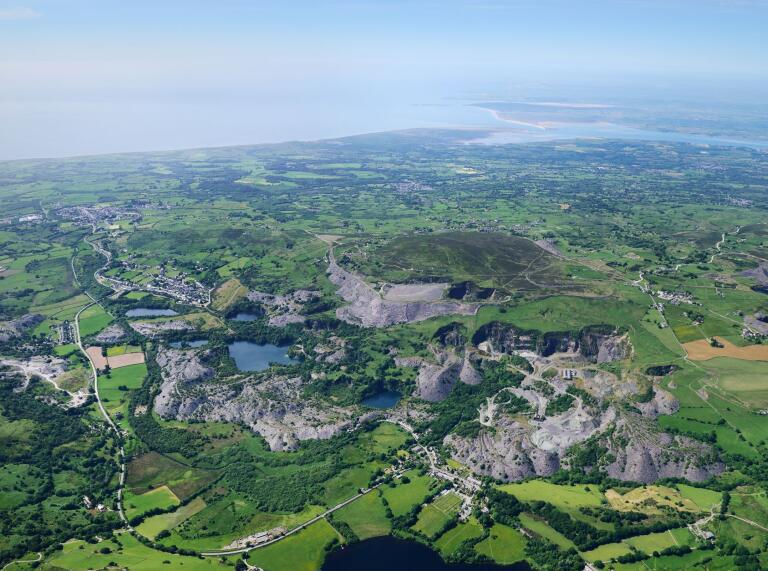 An aerial shot of a slate quarry valley, fields and reservoirs.