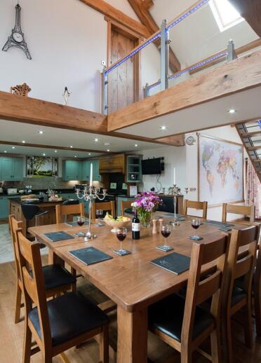Large dining table and kitchen inside an oak barn.