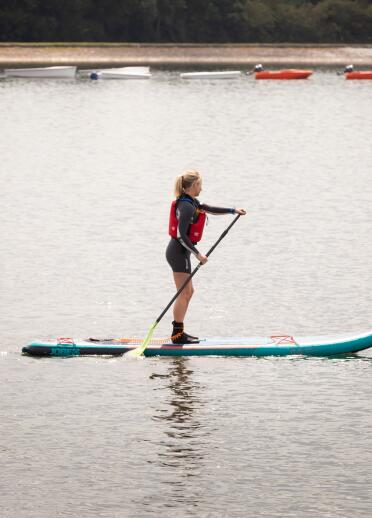 A woman on a stand up paddleboard on a reservoir.