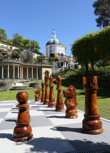 Large wooden chess pieces on a board in the gardens at Portmeirion.