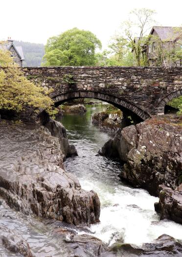 Aa river weaving through rocks under a stone bridge.