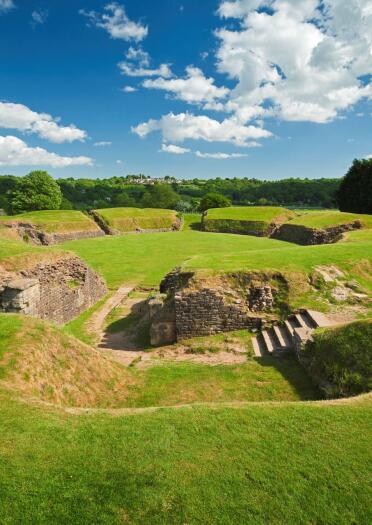 Remains of the Roman amphitheatre amongst lawned embankments.