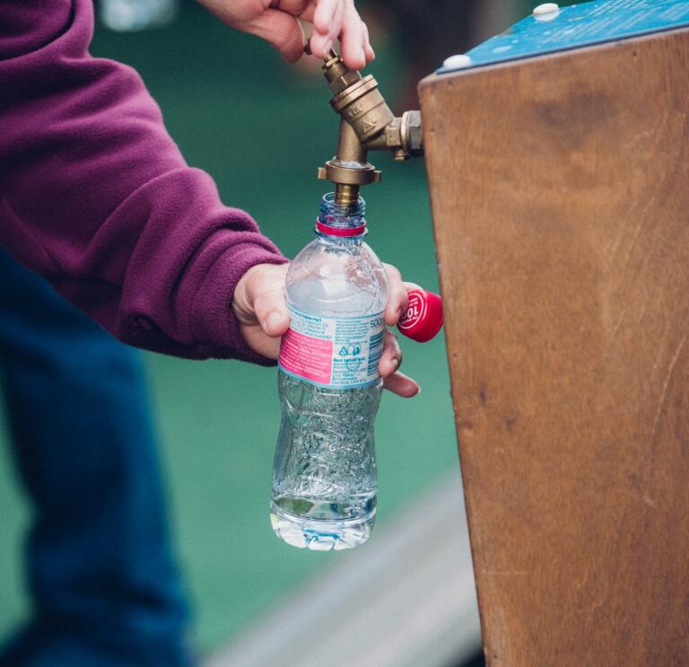 A water bottle being filled at a water station.