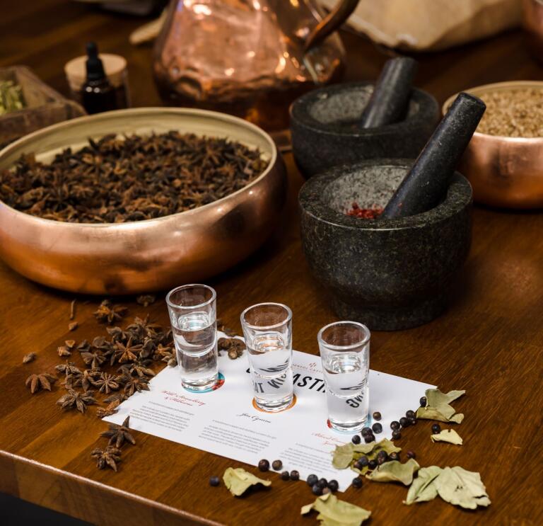 Gin taster shot glasses lined up next to bowls of spices.