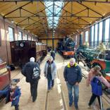 People viewing historic steam locomotives at museum.