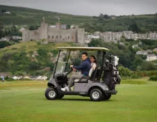 A golf buggy on a course with a castle in the background.