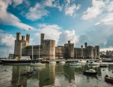 A castle and surrounded by an estuary with boats in the water.