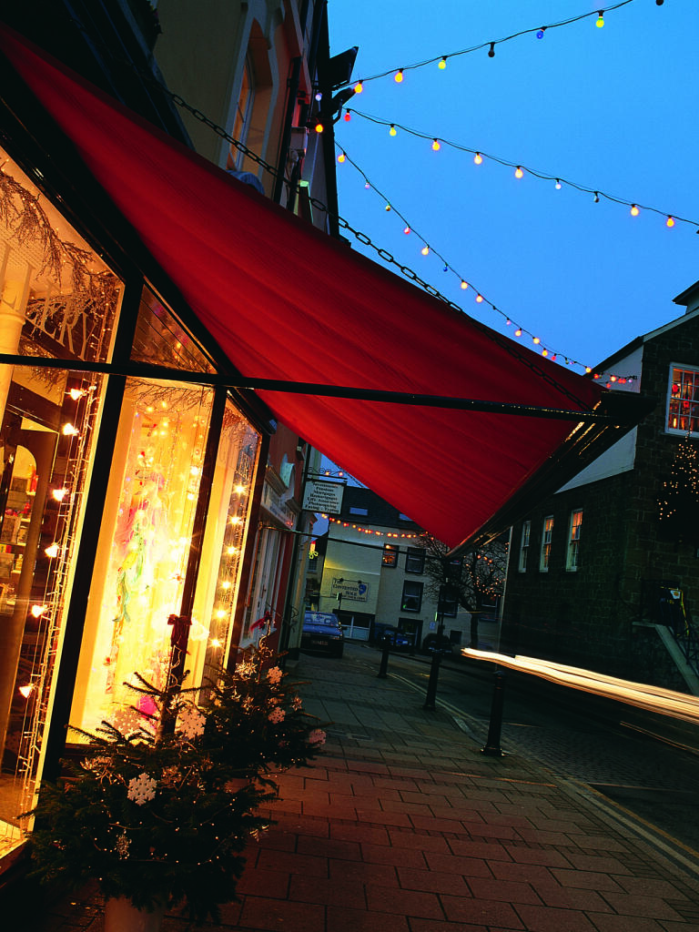 A shopping street in Narberth at dusk lit up with Christmas lights and decorations.