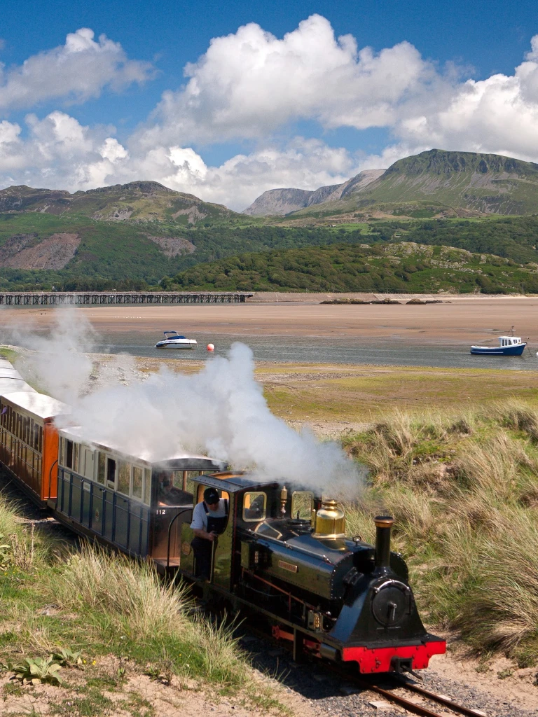 A Fairbourne Steam Railway train travelling along the Mawddach Estuary.
