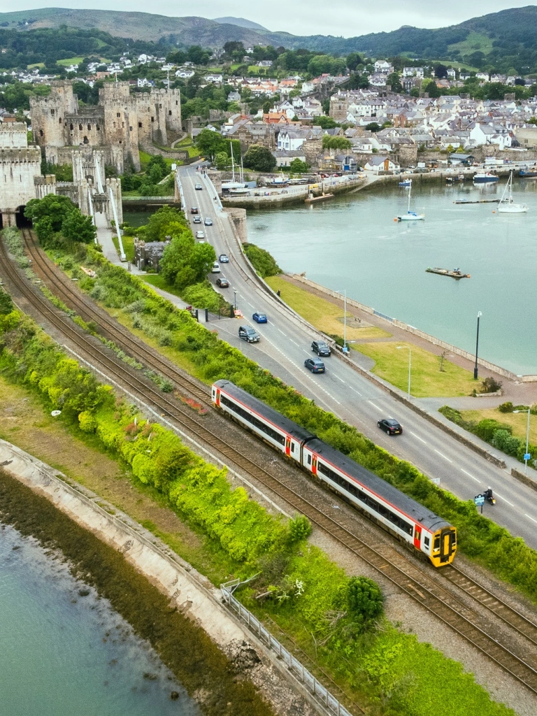 A train heading towards a tunnel beside a castle.