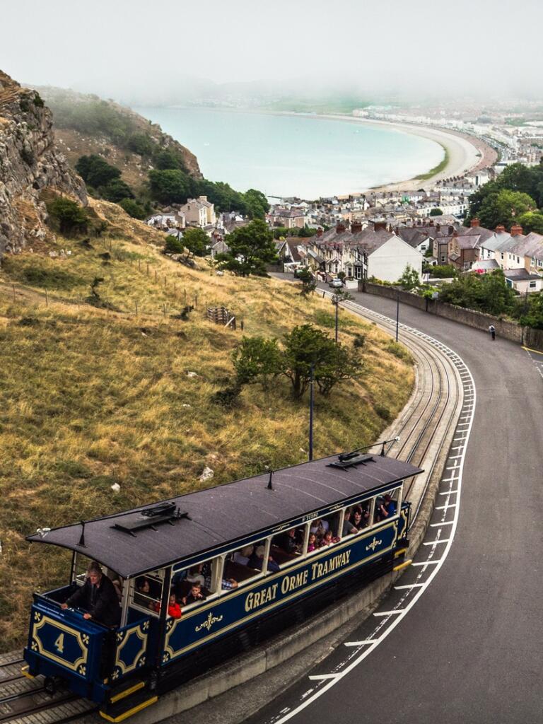 A tram climbing an orme with views of the coast below