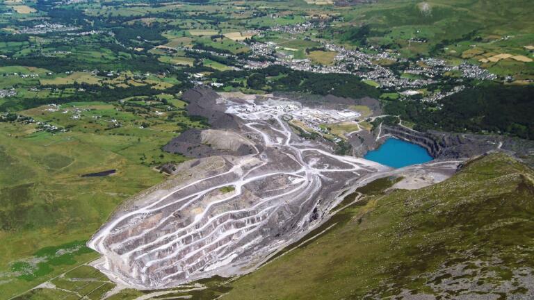 An aerial shot of an active quarry with a blue reservoir below.
