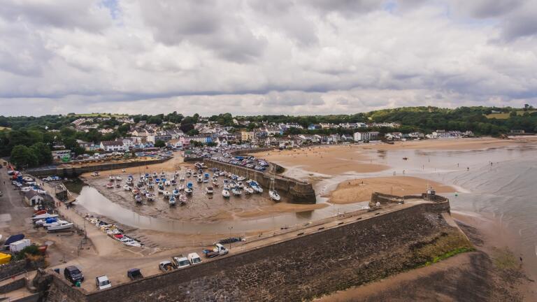 An aerial shot of a harbour and beach with the tide out.