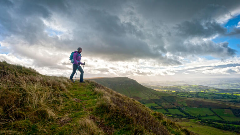 Female hiker on Hay Bluff, Black Mountains, Brecon Beacons, with a dramatic sky in the backdrop.