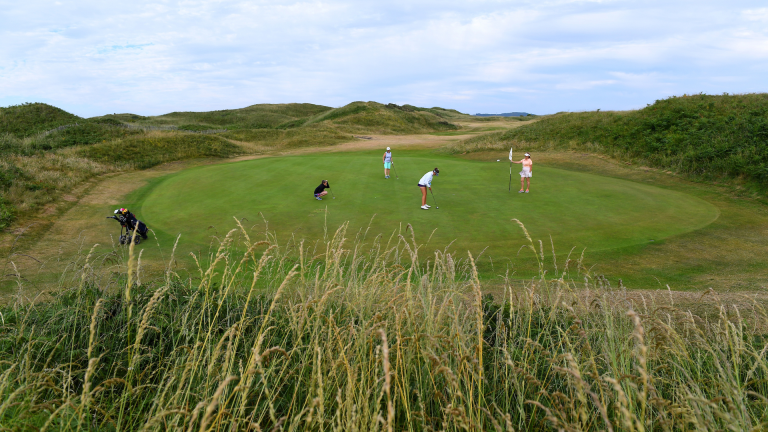 Four lady golfers on the green awaiting for a putt to be sunk at Pyle and Kenfig Golf Club.