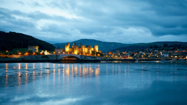 A castle and town lit up at dusk.