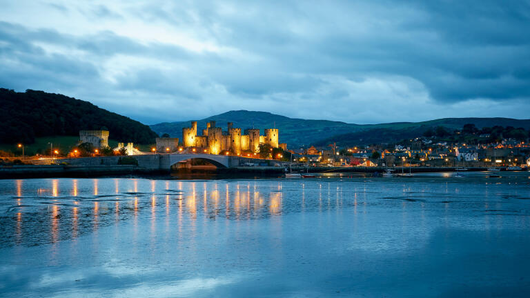 Conwy Castle and the town of Conwy lit up at dusk.