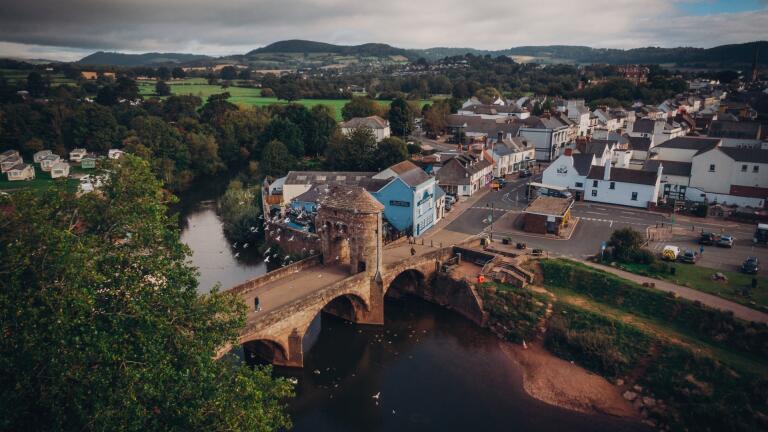Aerial shot of a river bridge leading to a town.