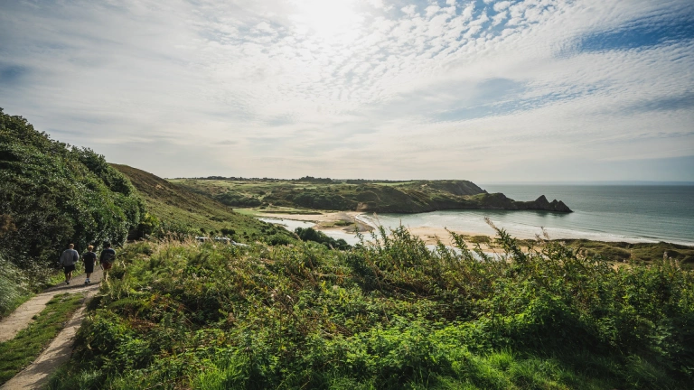 Walkers on a coastal path heading towards Three Clilff's Bay.