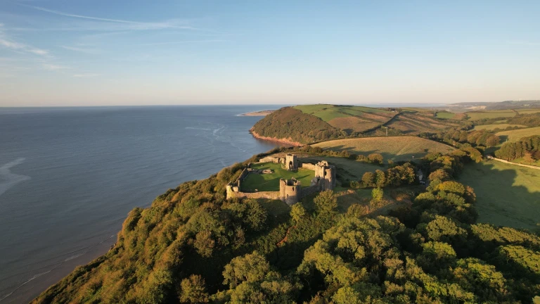 Aerial shot of a castle on a hill looking out toward the coast.