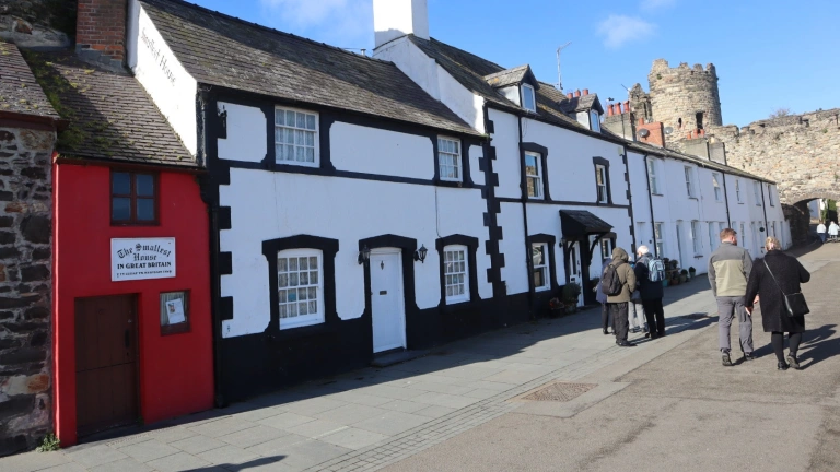 A street on a riverside quay featuring the smallest house in Britain.