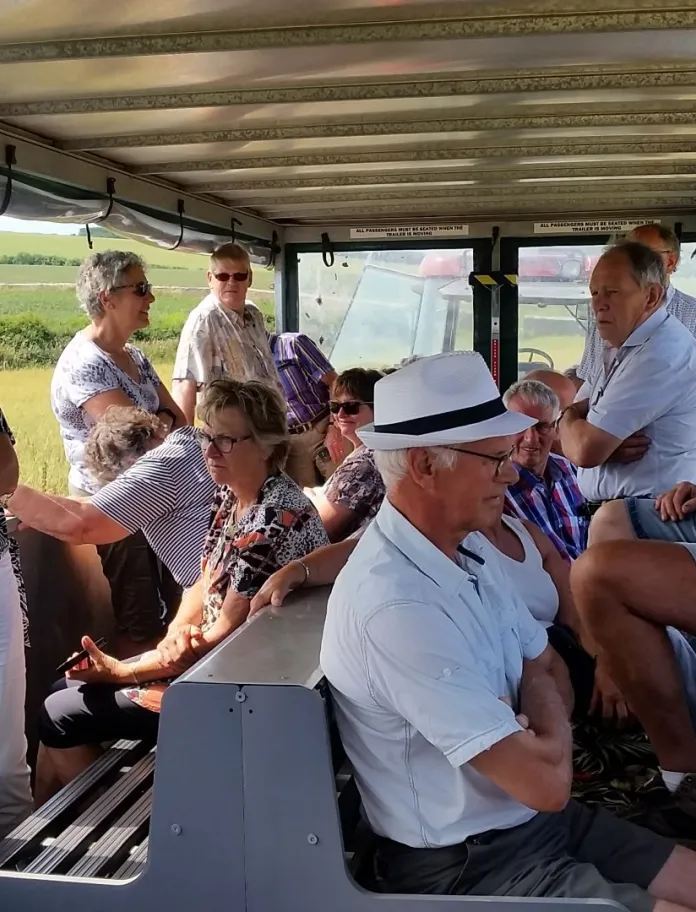 A group of people sitting on a trailer enjoying views of a farm.