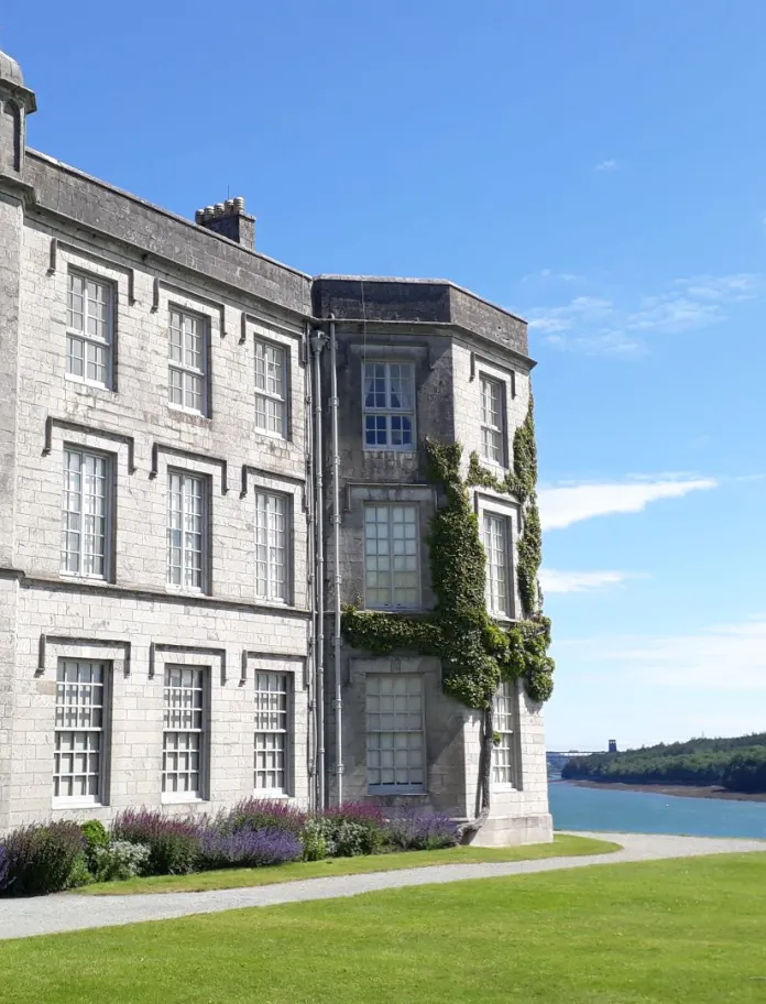 A grand house covered in Ivy with views of the river beyond.