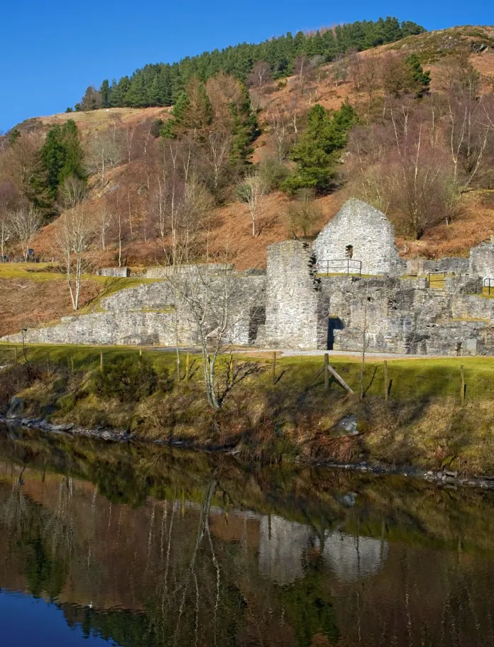 A view of Bryntail Lead Mine Buildings with the Afon Clywedog tributary in the foreground.