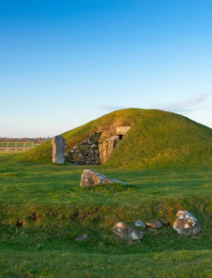 A green mound with an entrance made of stone leading into a burial chamber.
