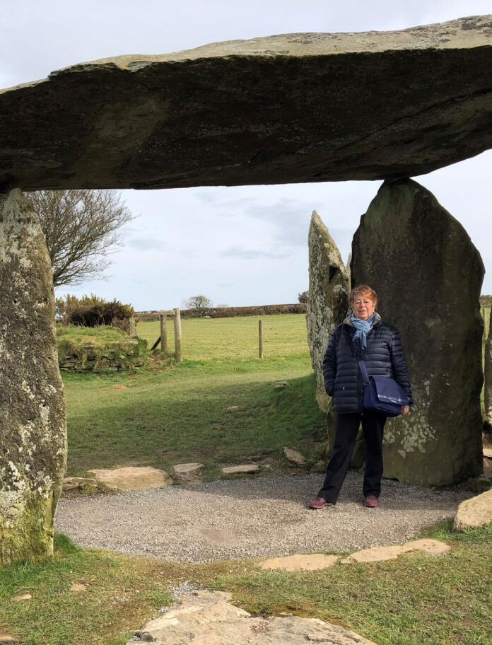 A lady standing under ancient stones at a burial chamber.