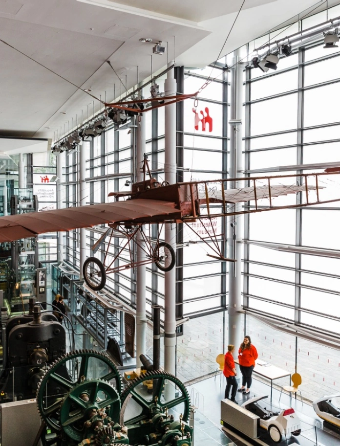 A historic glider hanging from the ceiling in a museum.