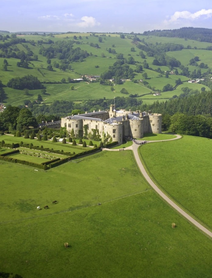 An aerial view of Chirk Castle and gardens with mountains in the background.