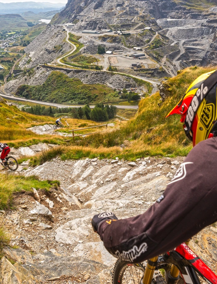 Two mountain bikers at the start of a track looking down to the quarry and village.