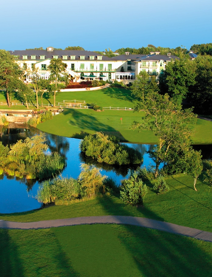 A hotel with a beautiful lake and grounds in front.