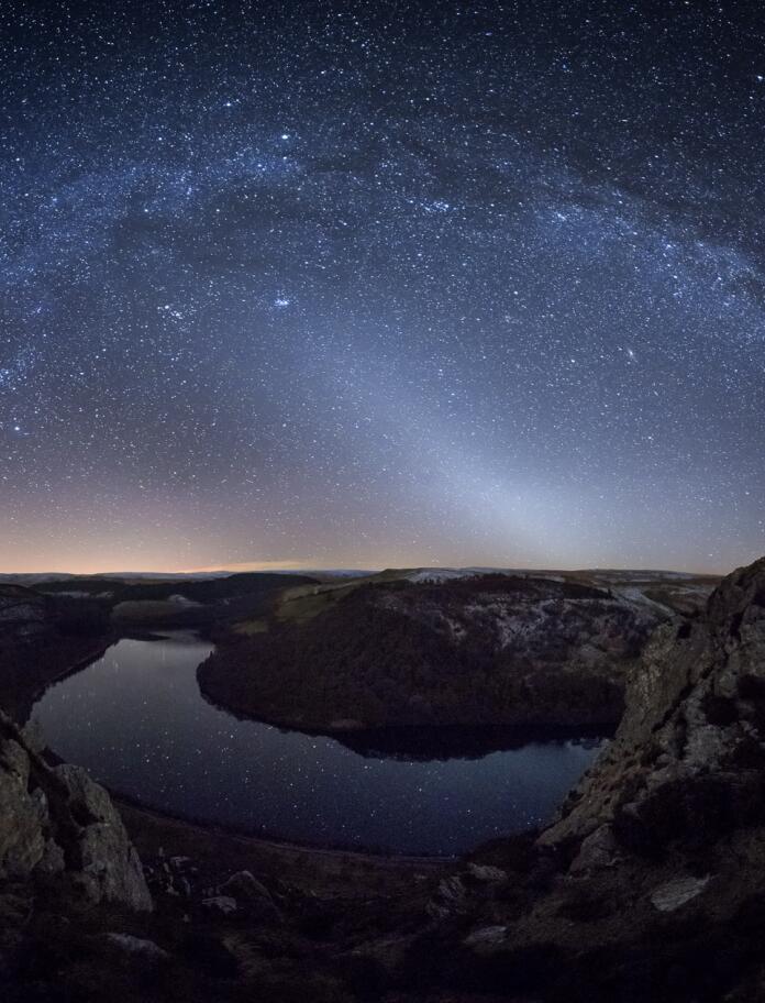 Stars in the night sky over a valley of water.