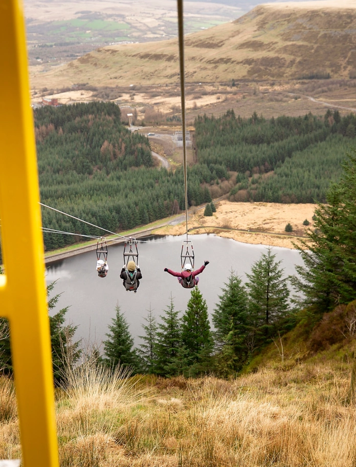 People on zip wires zipping across a mountainous landscape.