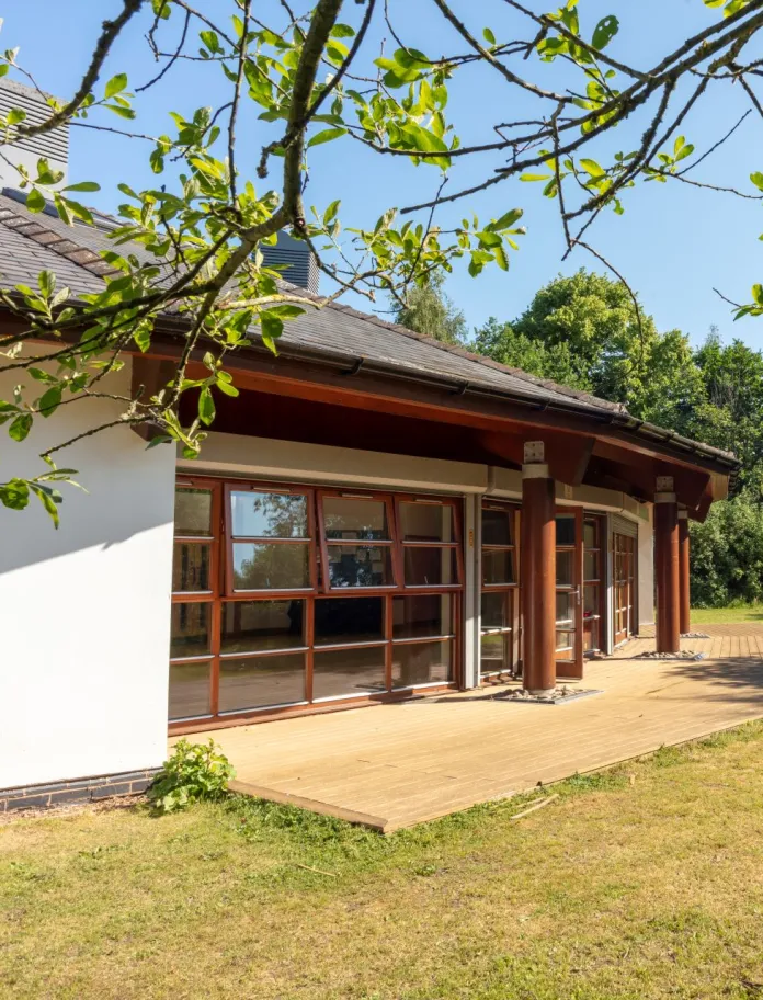External shot of a conservatory surrounded by green trees.