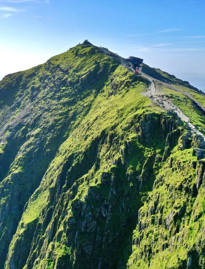 A diesel train approaching the summit of a mountain.