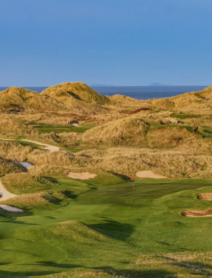 A golf course with views of the sea beyond.