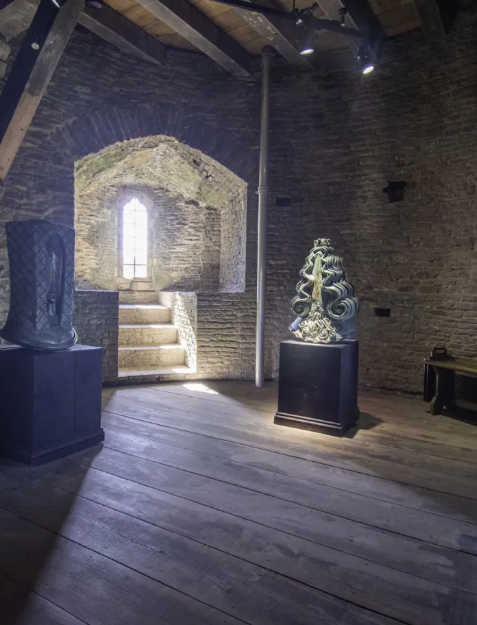 Statue heads of knights inside a medieval castle, with sunlight streaming through the window.