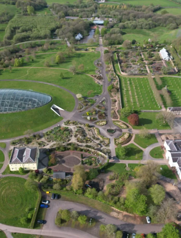 An aerial shot of a domed glass greenhouse at a botanic garden.