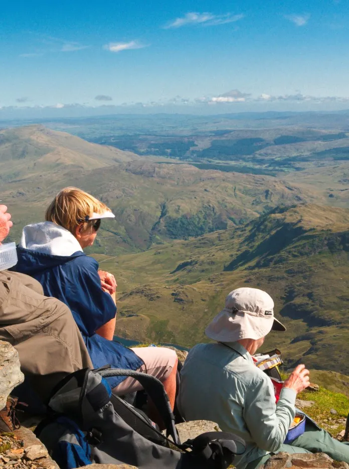 Walkers resting and eating their packed lunch at the summit of Snowdon.