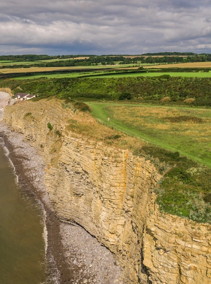People walking along the Wales Coast Path showing dramatic cliffs and shorline.