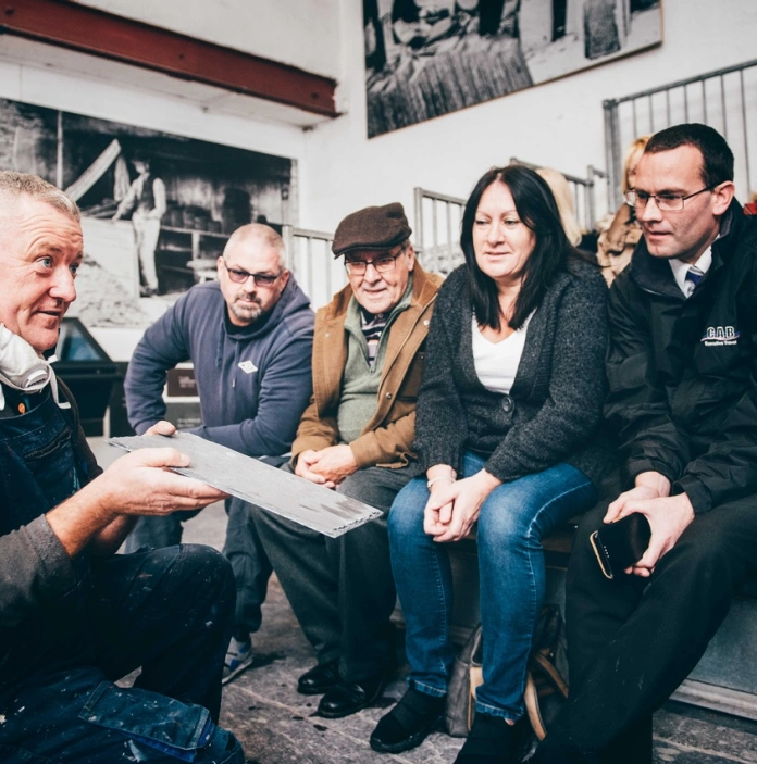 A group of people watching a demonstration on slate splitting.