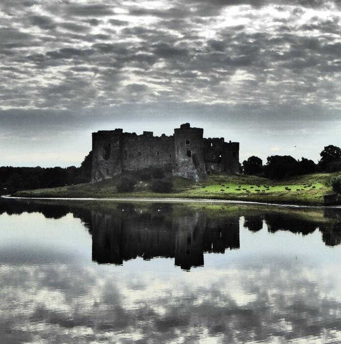 A castle reflecting in the water with dramatic clouds above.