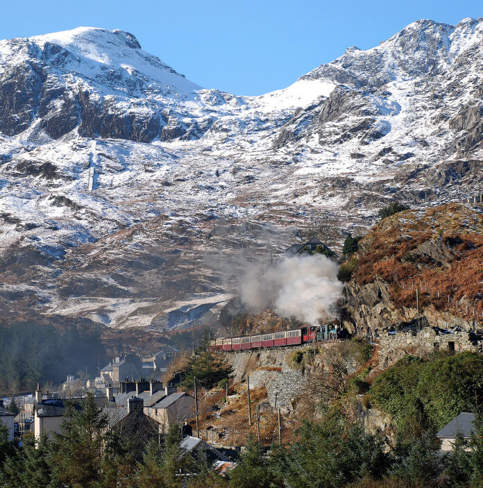 A steam train passing through a snowy slate quarry.