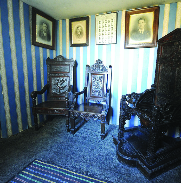 Image of a room with three large bardic chairs and family pictures on the wall.